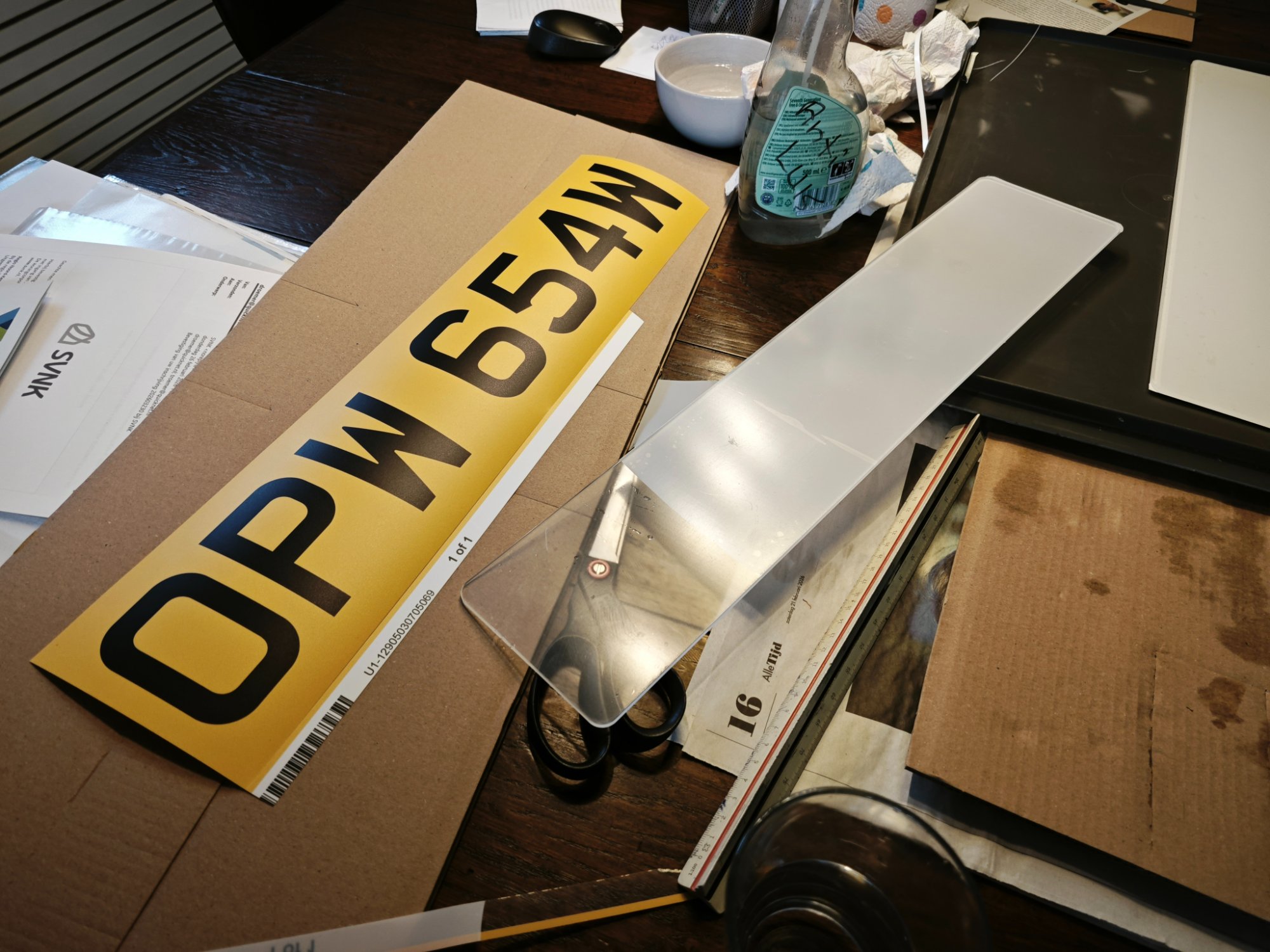 Het vinyl-ontwerp van de OPW 654W kentekenplaat naast de doorzichtige acrylplaat